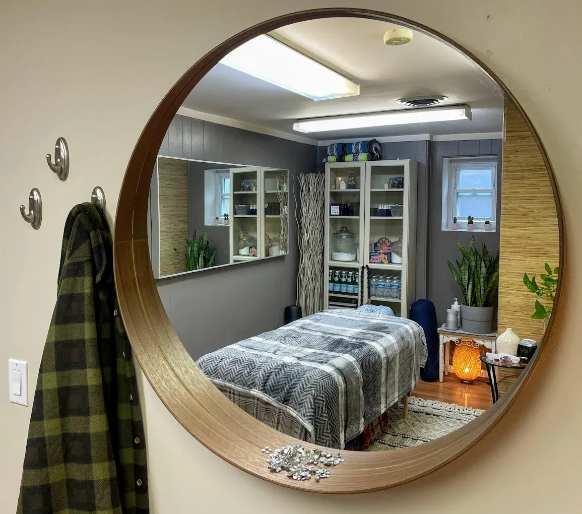 Treatment room through a large round wood-framed mirror in daytime natural light