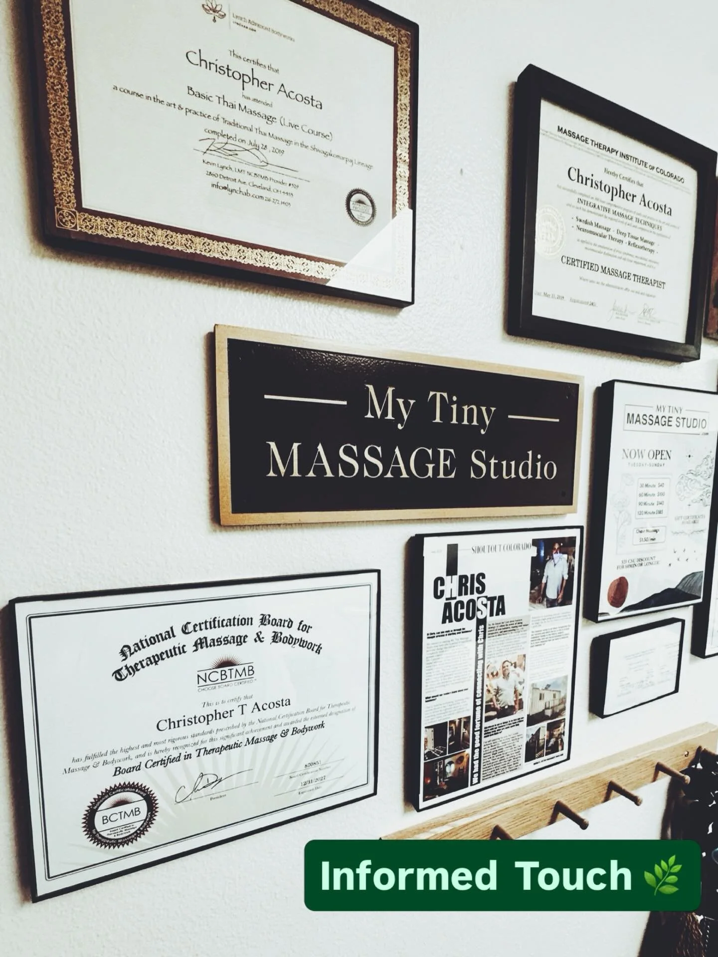 Wall of framed certifications for Christopher Acosta — NCBTMB Board Certification, Massage Therapy Institute of Colorado diploma, My Tiny Massage Studio sign